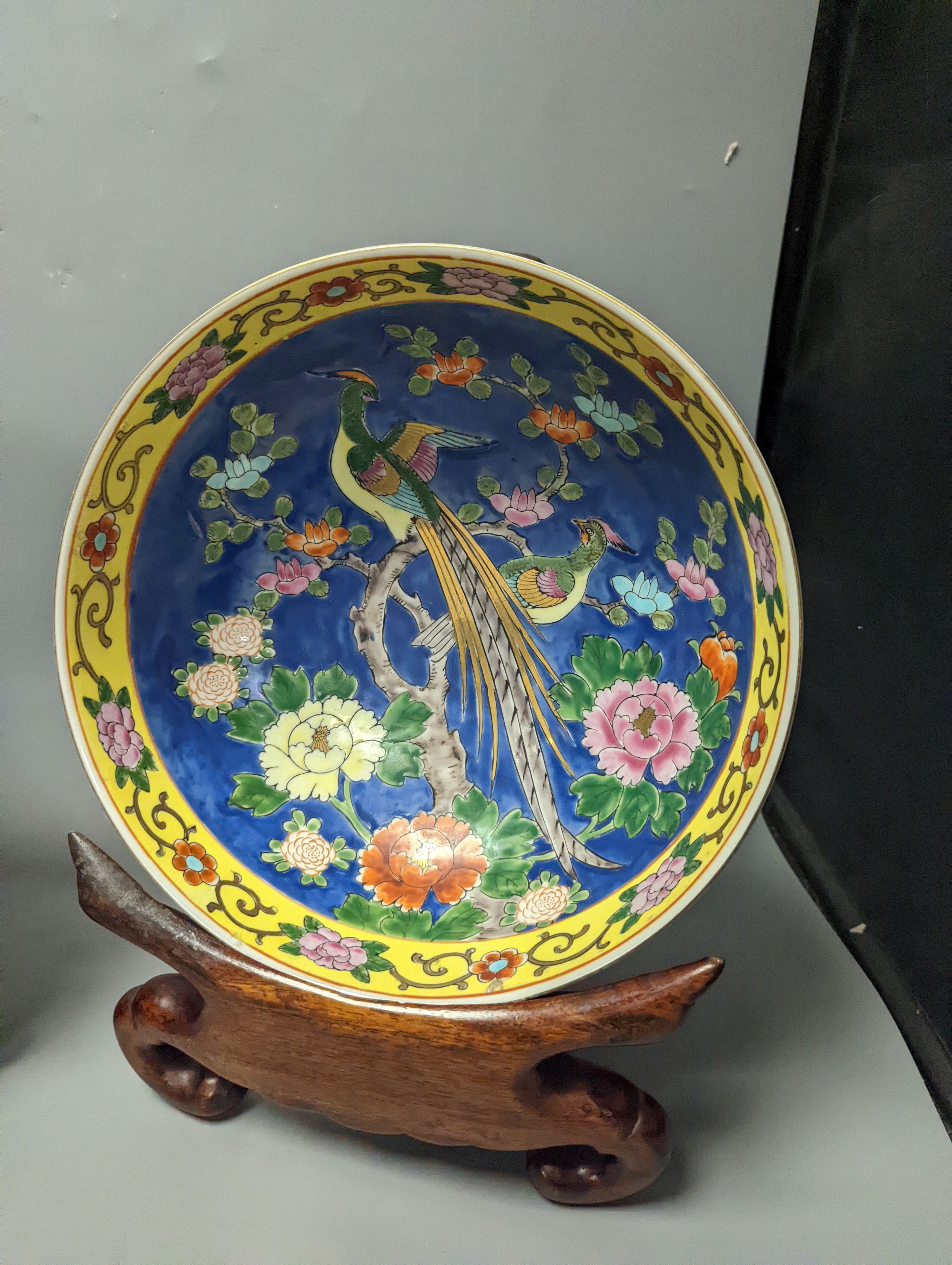 A Japanese Satsuma vase of a geisha and two Japanese yellow and a blue ground bowls each on wooden stands, Stands 32 cms high x 26cms deep.